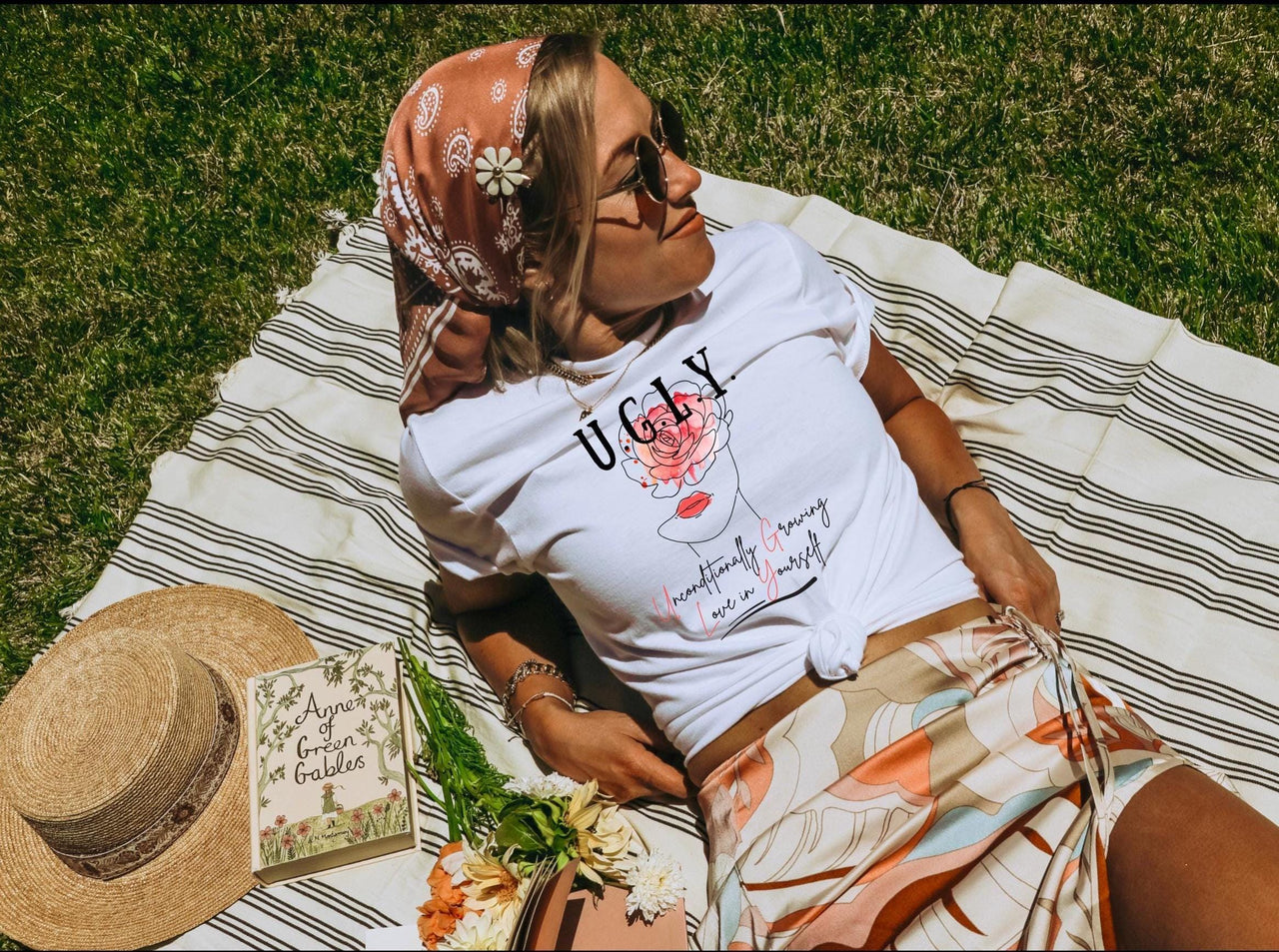 a woman laying on top of a blanket next to a hat