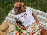 Thumbnail for a woman laying on top of a blanket next to a hat