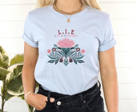 Thumbnail for a woman wearing a light blue t - shirt with a pink flower on it