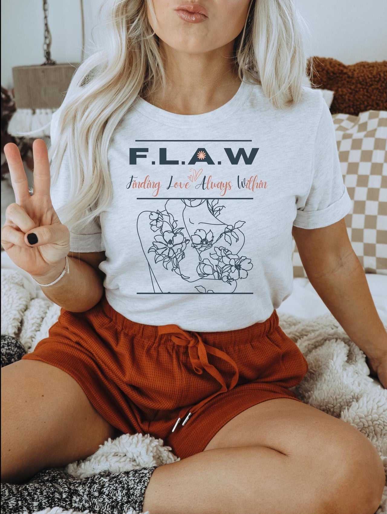 a woman sitting on a bed holding a peace sign