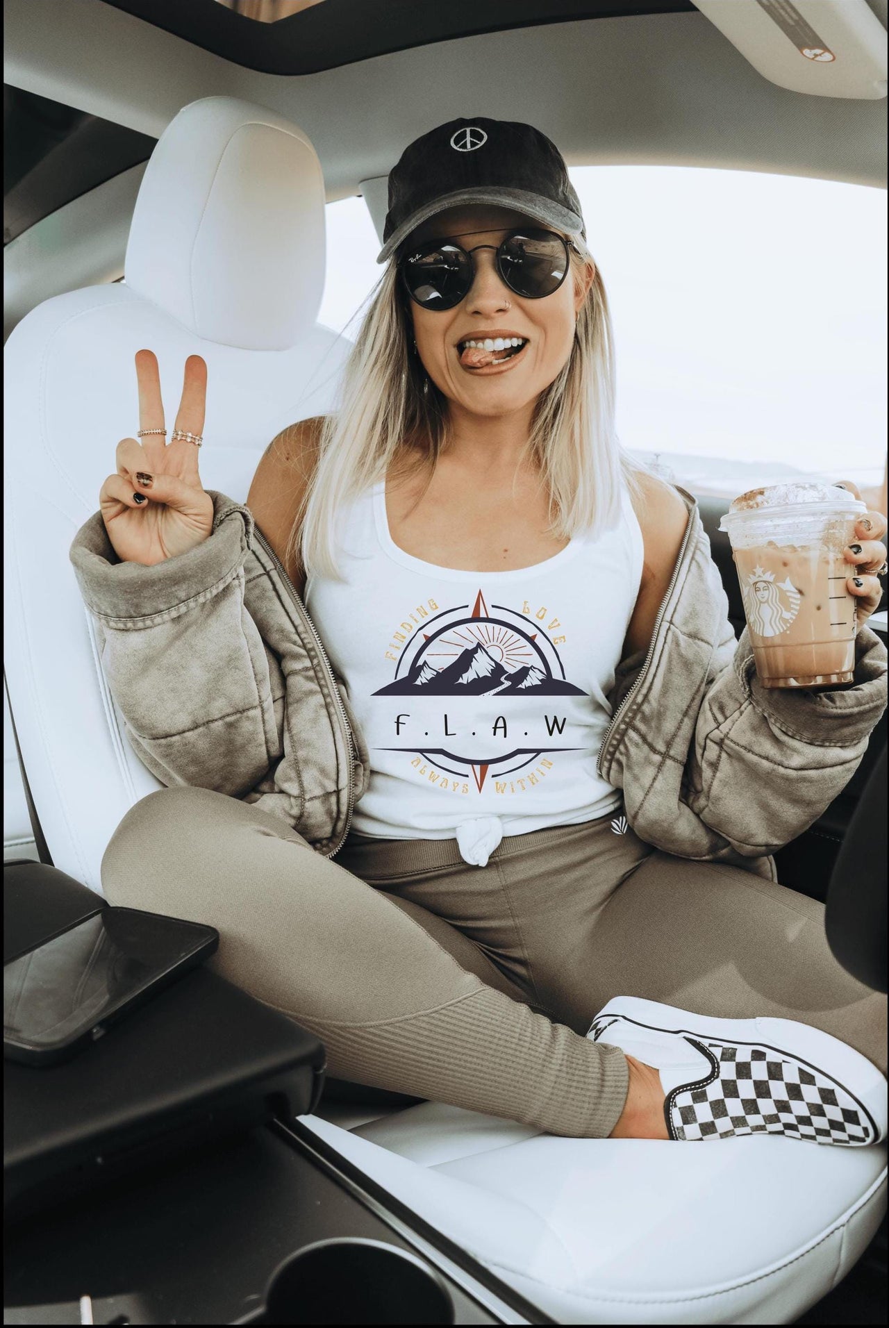 a woman sitting in the back of a car holding up a peace sign