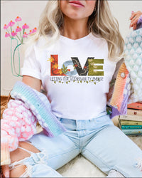 Thumbnail for a woman sitting on a pile of books wearing a t - shirt that says love