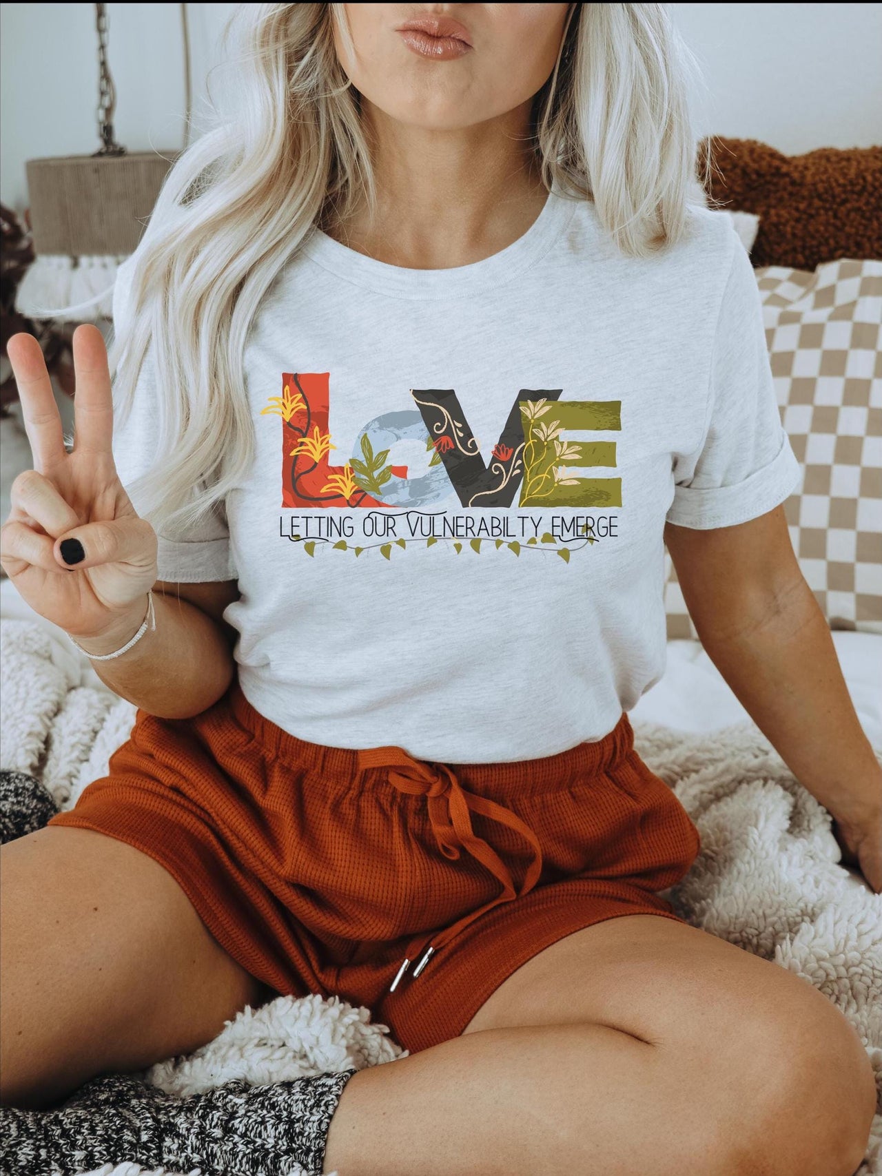 a woman sitting on a bed holding a peace sign